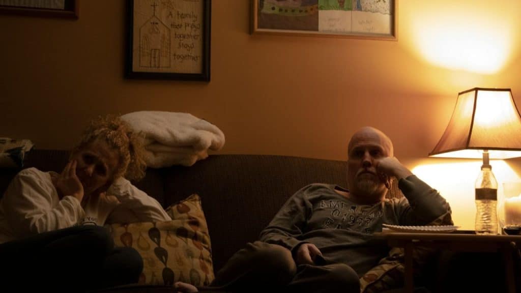 A bored-looking couple sitting on a couch.