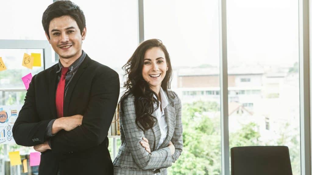 A business couple standing with crossed arms back to back.