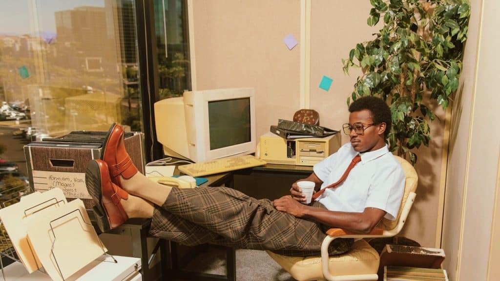 A man sitting in a chair in front of a computer desk.