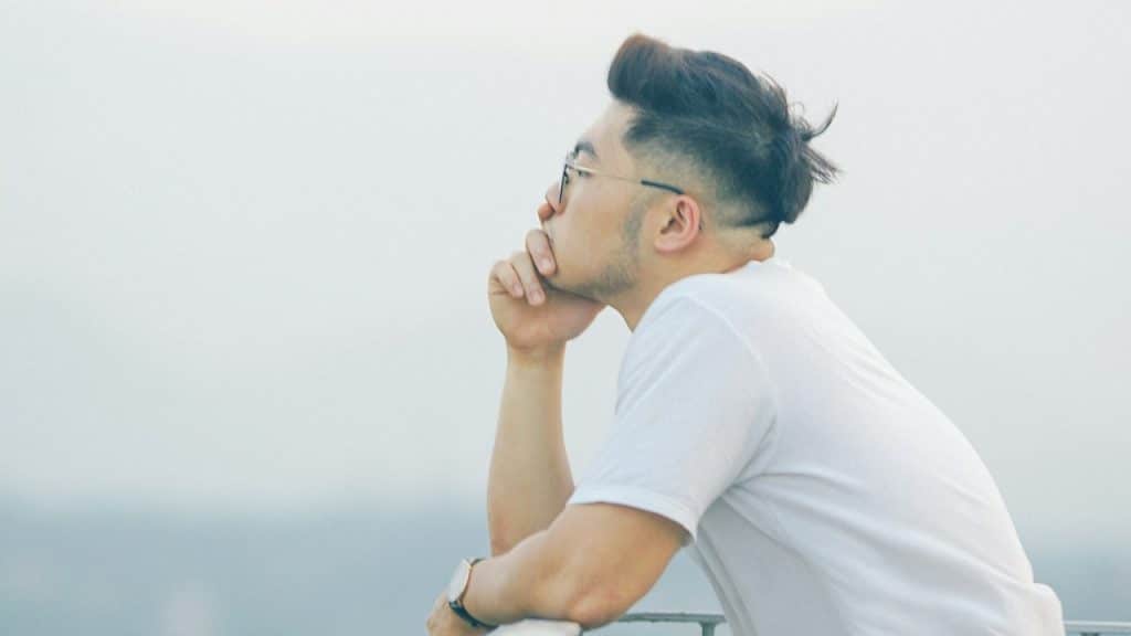 A man wearing sunglasses gazing at the horizon while looking lost in thought.