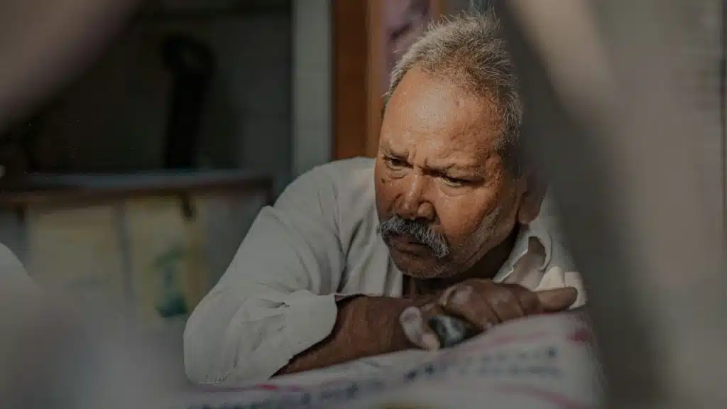 Older man with a mustache leaning on his hands with a serious expression.