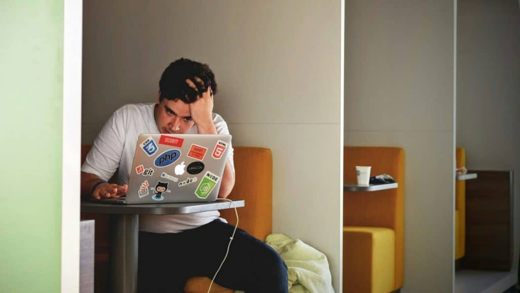A man looking frustrated working on his laptop.