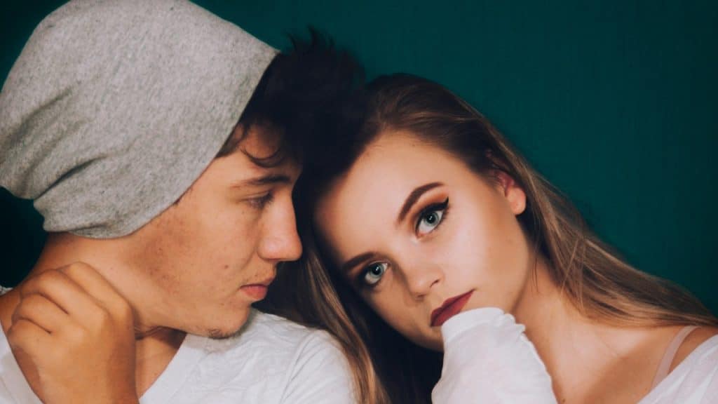 A man looking uneasy while a woman leans on his shoulder.