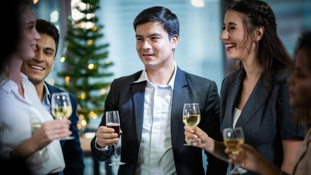 A group of people dressed in business attire smiling and holding champagne glasses.