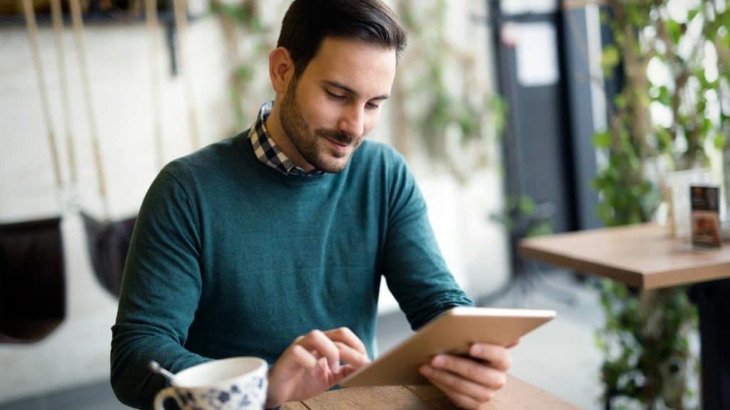 A using a tablet while sitting inside a cafe.
