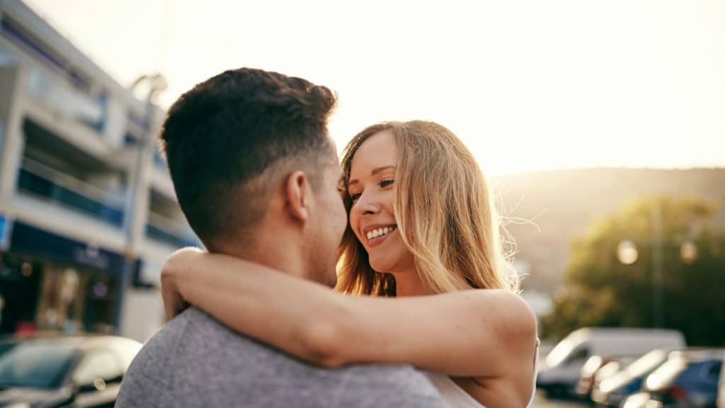 Happy couple hugging outdoors on a sunny day.
