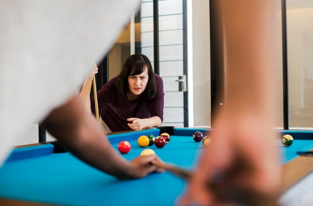 The couple is playing a game of pool.