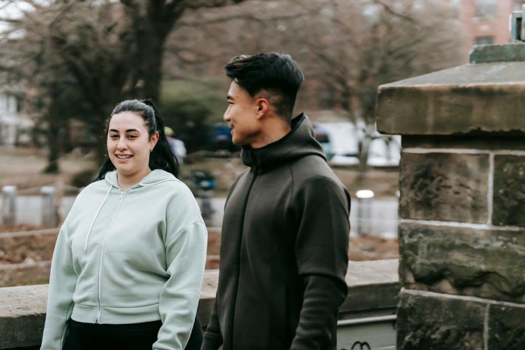 The man and the woman are talking while walking in the park.