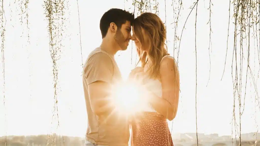A man and woman holding hands while standing together at sunset.