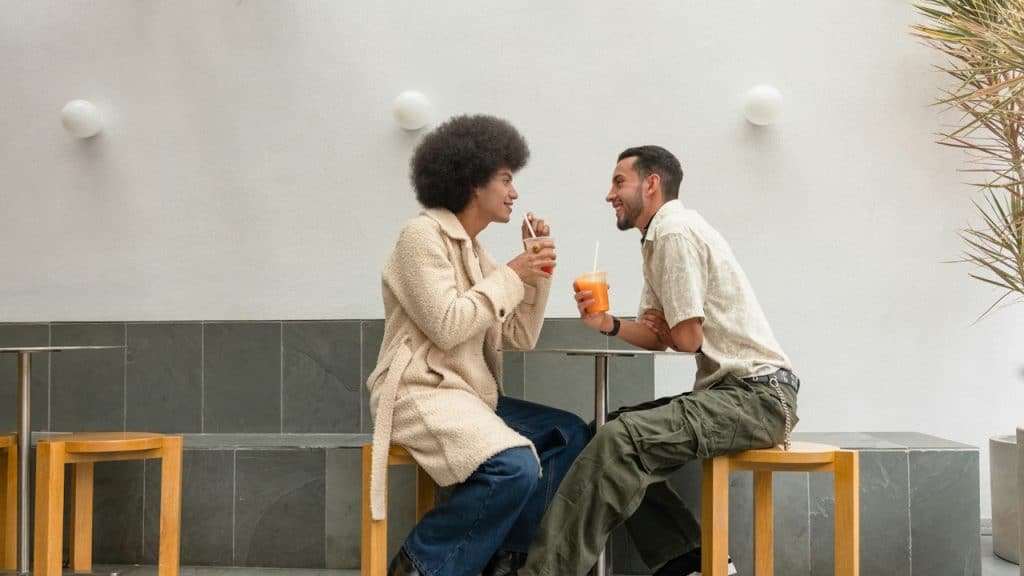 A couple sitting at a table and drinking juice.