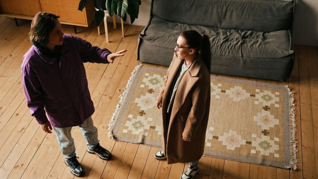 Overhead view of two people standing in a living room, one gesturing to the other.