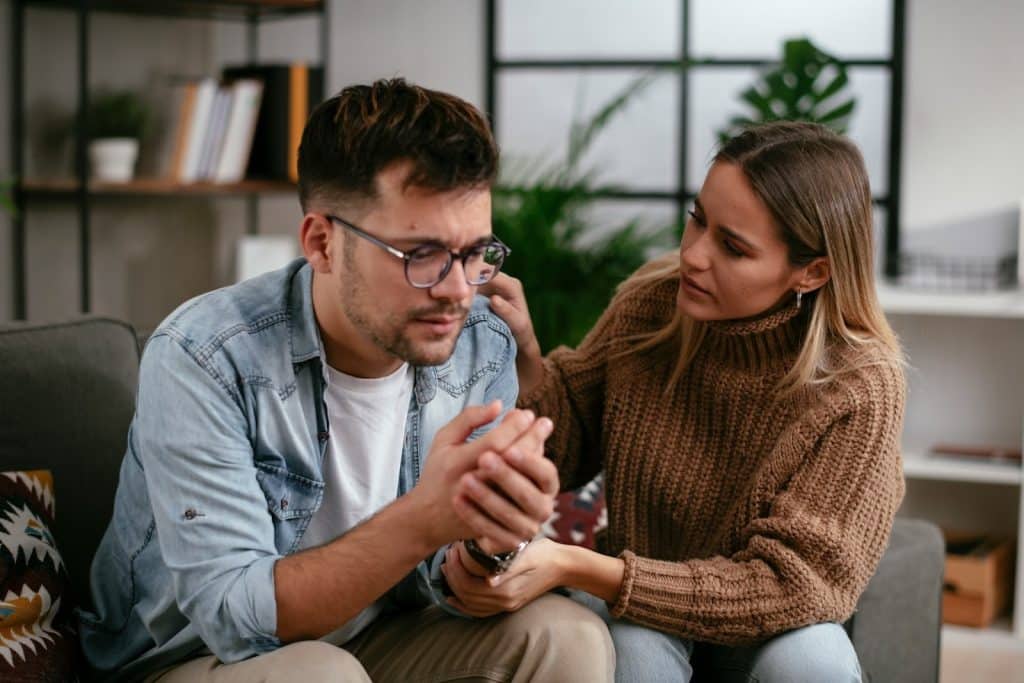 The woman is comforting her sad boyfriend.