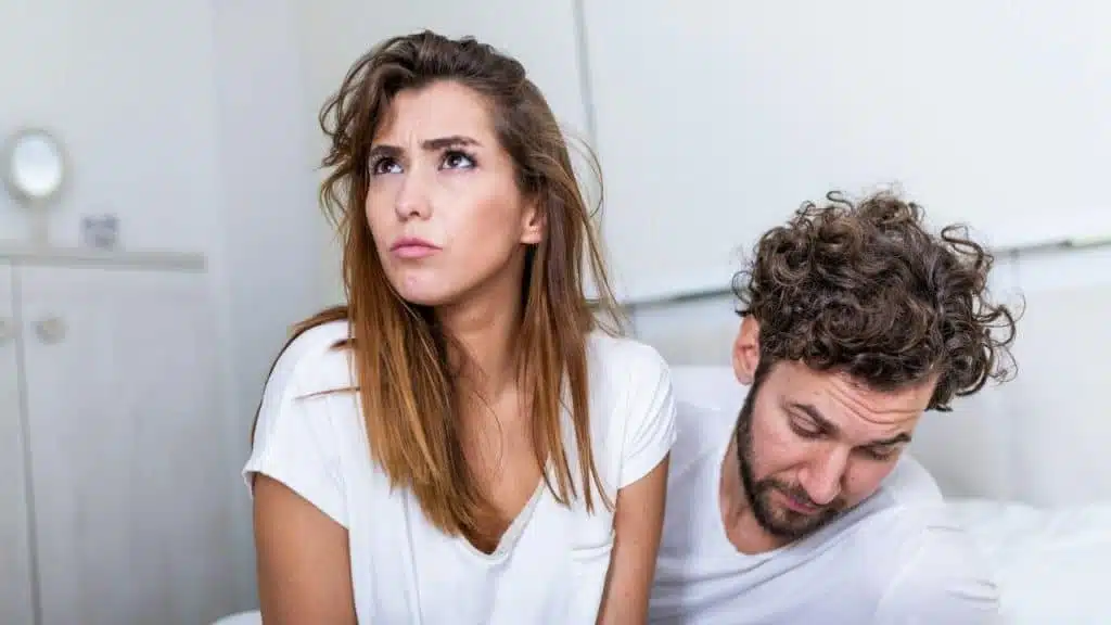 A woman with a frustrated expression looks up while a man looks down beside her.