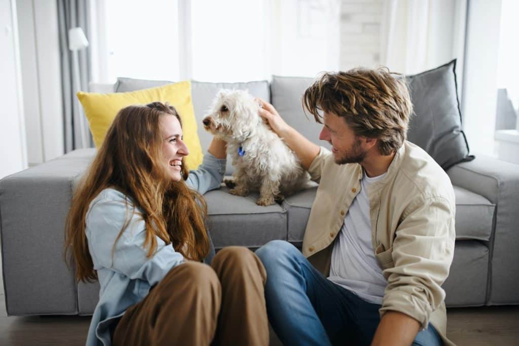 A couple talking in the living room with their dog.
