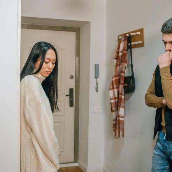 An upset couple standing in the hallway.