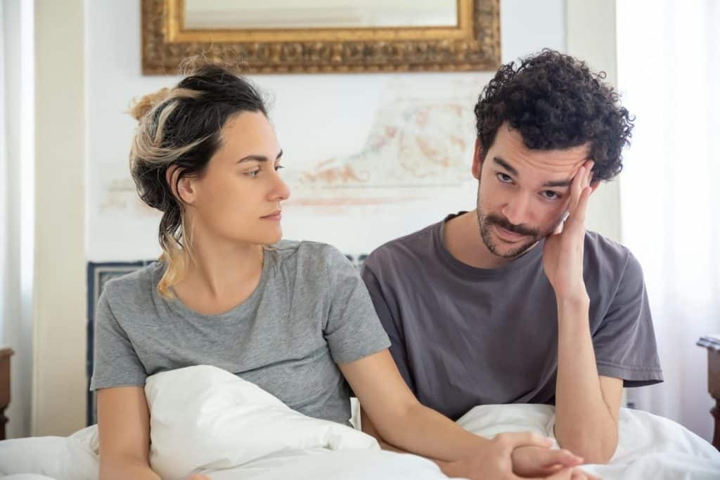 A couple sitting together on bed.