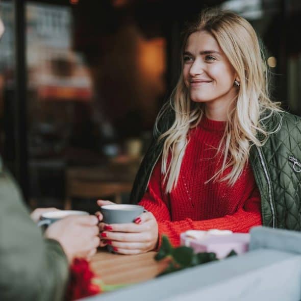 A woman holding a cup of coffee and looking at her date.