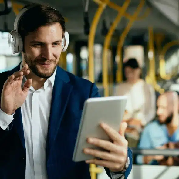 A man waving on a video call while commuting to work.