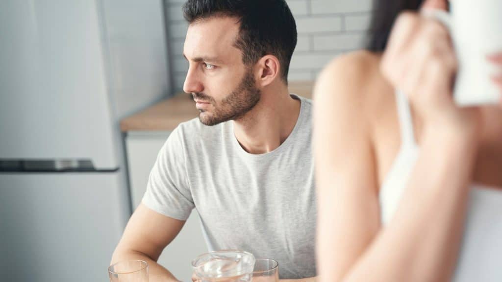A thoughtful man sitting at a kitchen table.