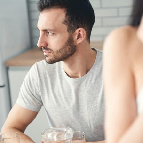 A thoughtful man sitting at a kitchen table.