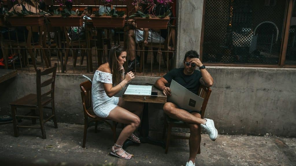 A couple sitting at a table outdoors and looking at menus.