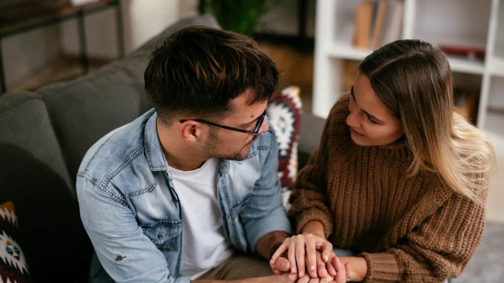 A woman comforting her sad boyfriend, who is having some problem.