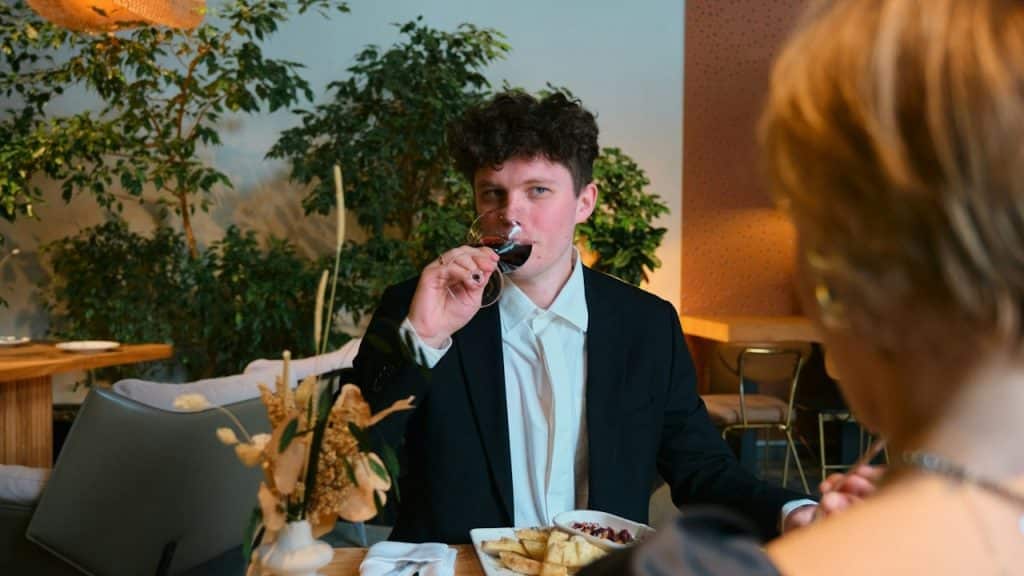 A man sipping beer from a glass while looking at a woman.