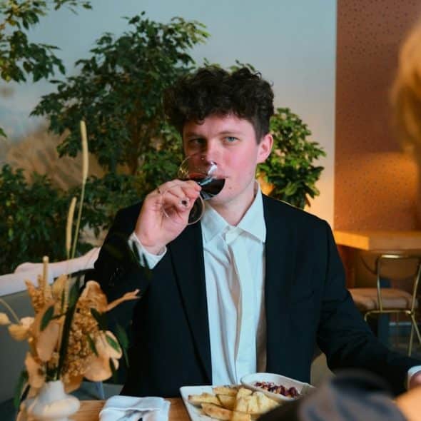 A man sipping beer from a glass while looking at a woman.