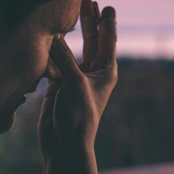 A close-up of a person touching their face with a tired or stressed expression.