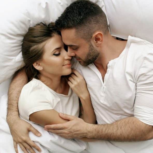 A couple cuddling in bed together