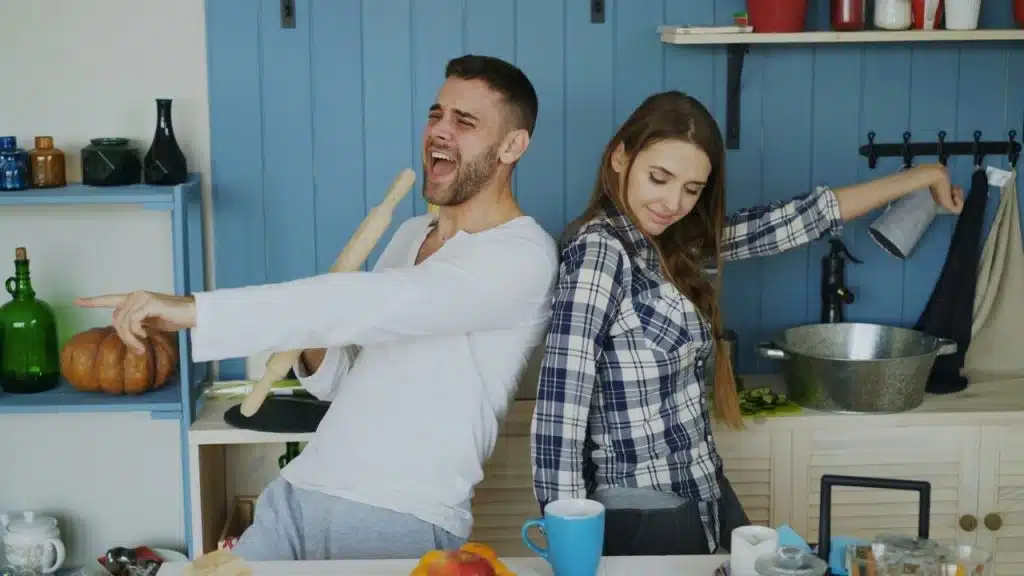 A couple dancing and singing together in the kitchen