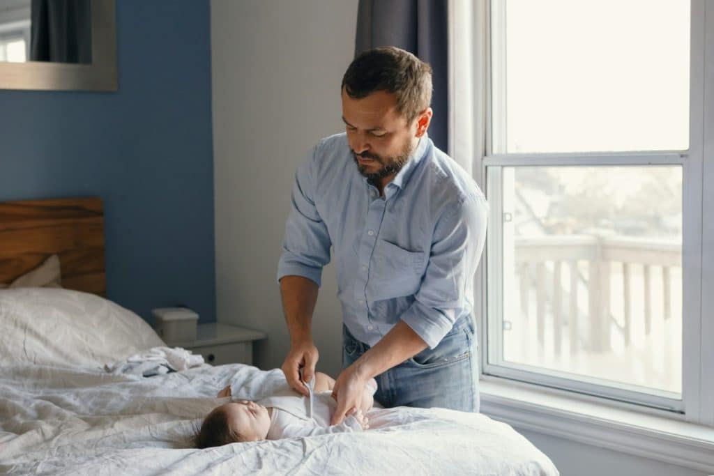A mature dad changing the diaper of his newborn baby.