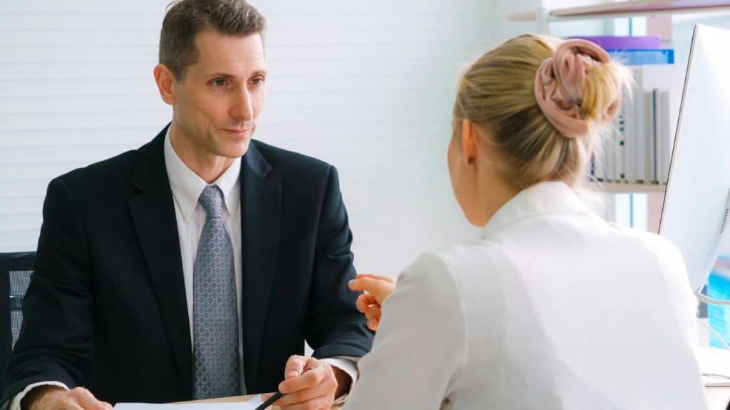 A man in a suit listens intently to a woman across a desk.
