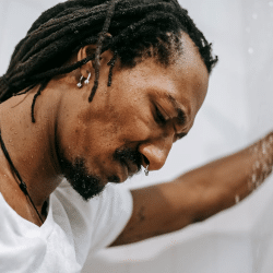 Crop frustrated black man standing in shower cabin