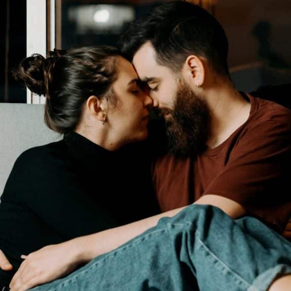 A couple sitting on the couch and having an intimate moment.
