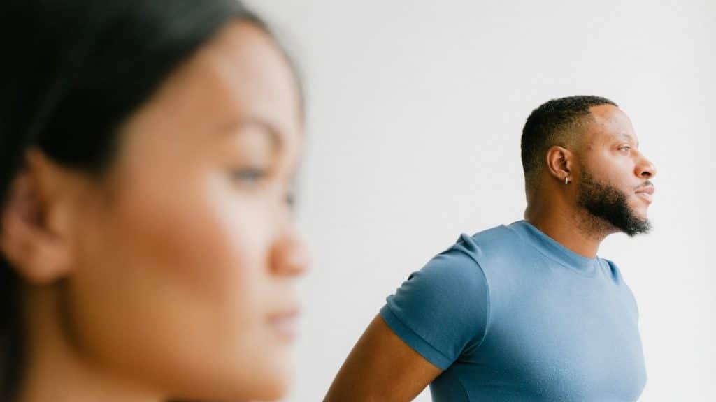 A stressed man standing next to a woman in a blue shirt.
