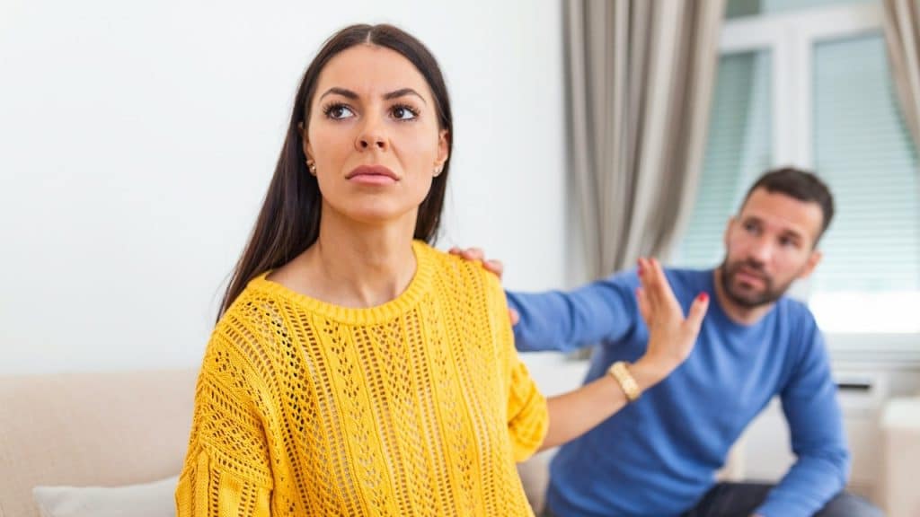 A stressed man saying sorry after a quarrel with his frustrated wife.
