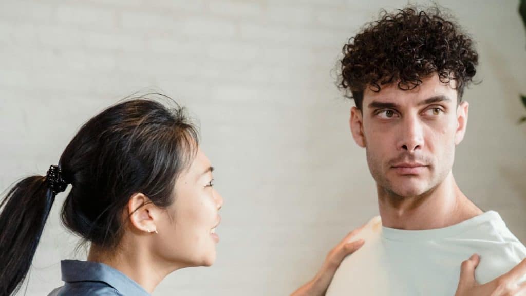 A woman talking to a man with curly hair.