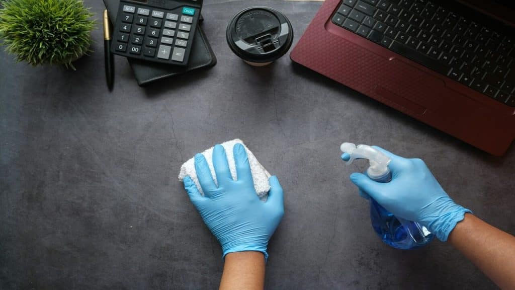 A person disinfecting the desk