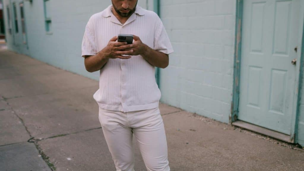 A person walking on a sidewalk while looking at their phone.
