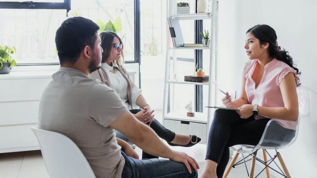 A woman psychologist with a couple as patients in therapy talking about mental problems.