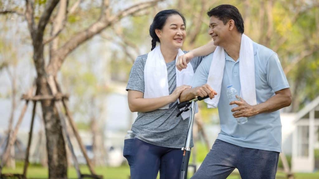 A couple with a scooter together outdoors.