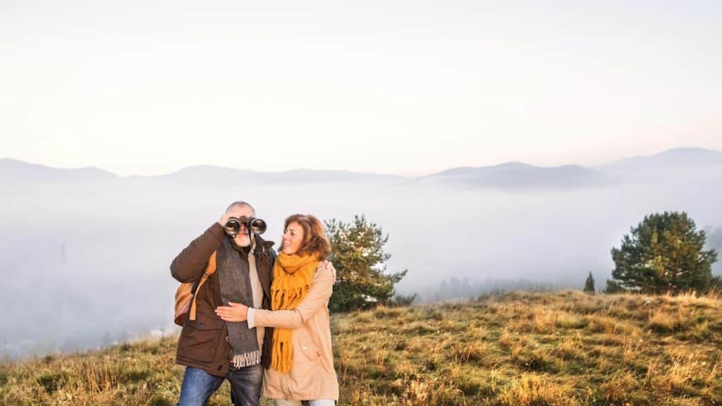 An active senior couple on a walk in autumn and an old man looking through binoculars.