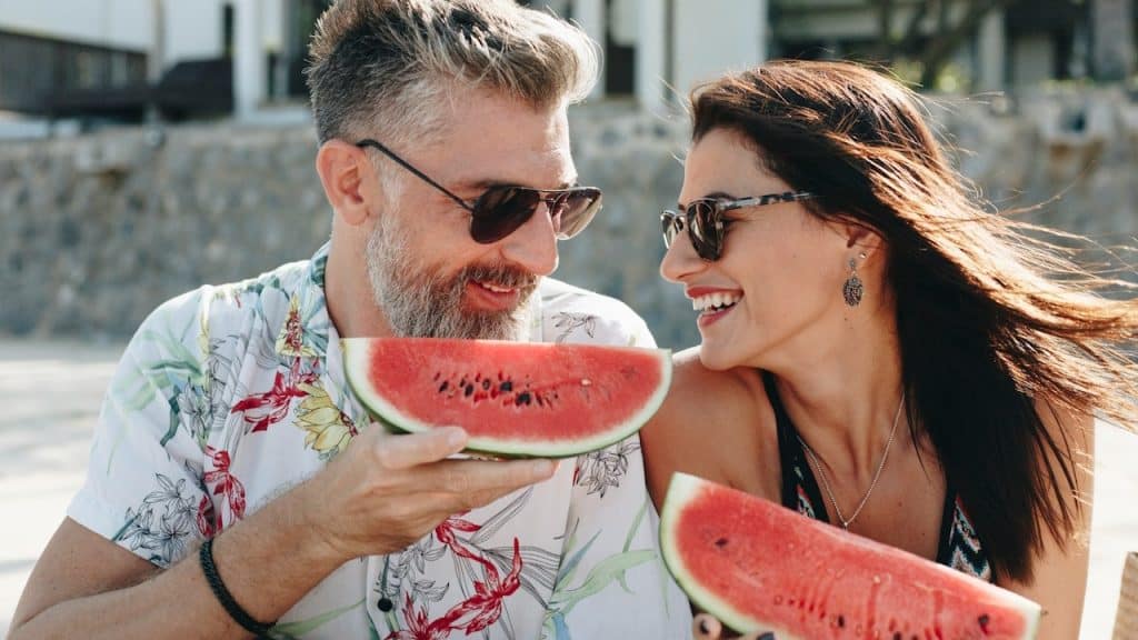 A couple eating watermelon at the beach.