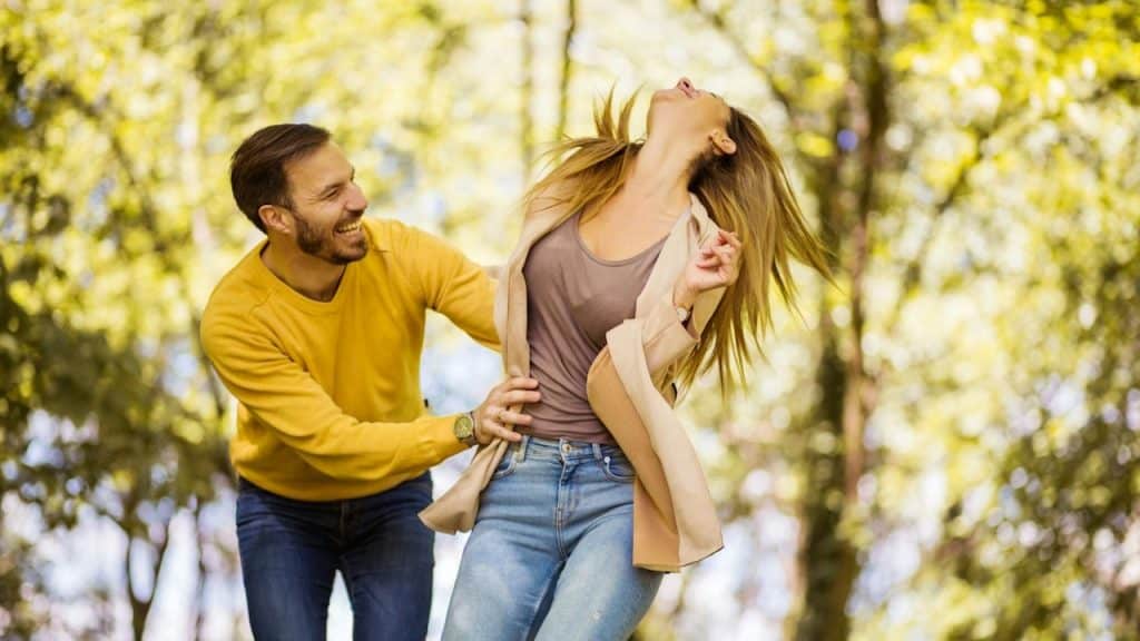 A man tickling a woman outdoors. 