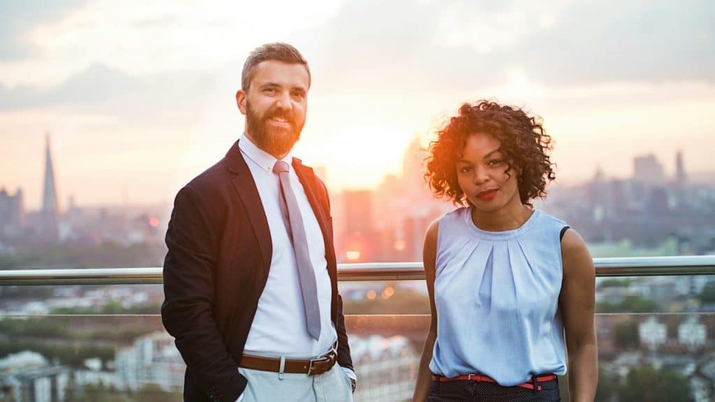 Businesspeople standing against a London rooftop view at sunset.