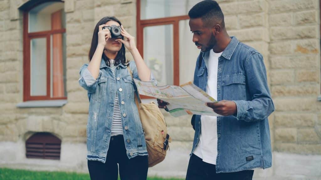 A woman takes a photo while the man looks at a map.