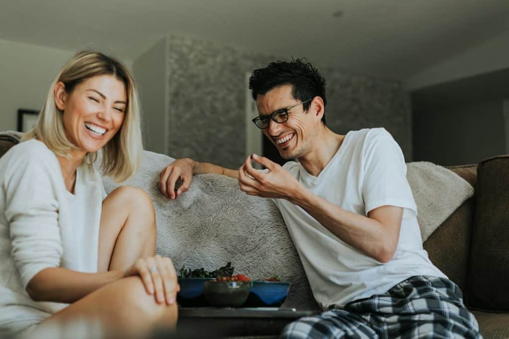 The couple is laughing together while hanging out at home.