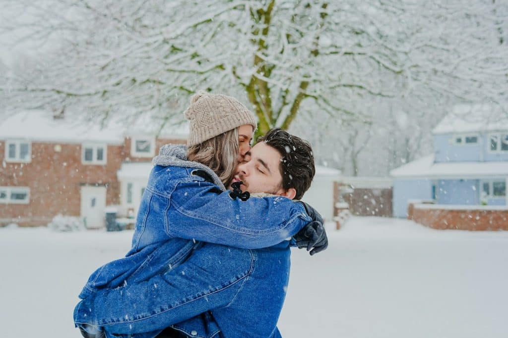 The couple is hugging each other while outdoors.