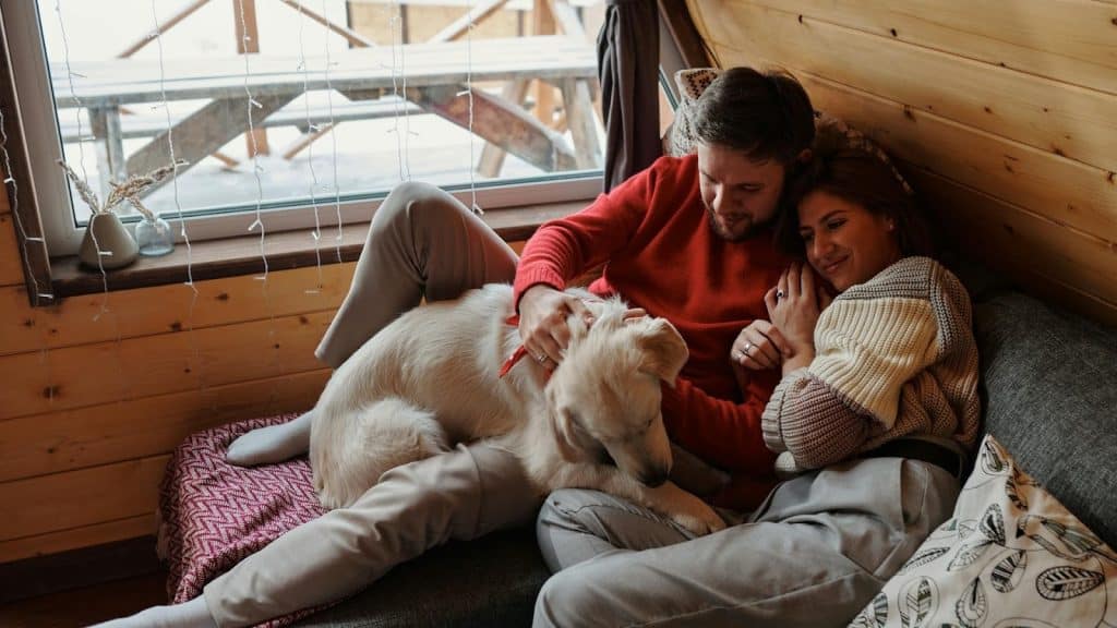 The couple is snuggled while looking at their dog.